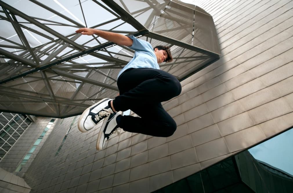 A person performs a high jump in an urban setting