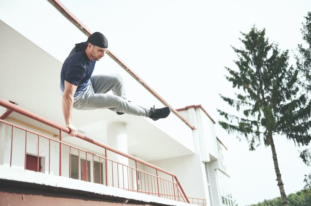 A man performs a speed vault over a railing in an urban setting