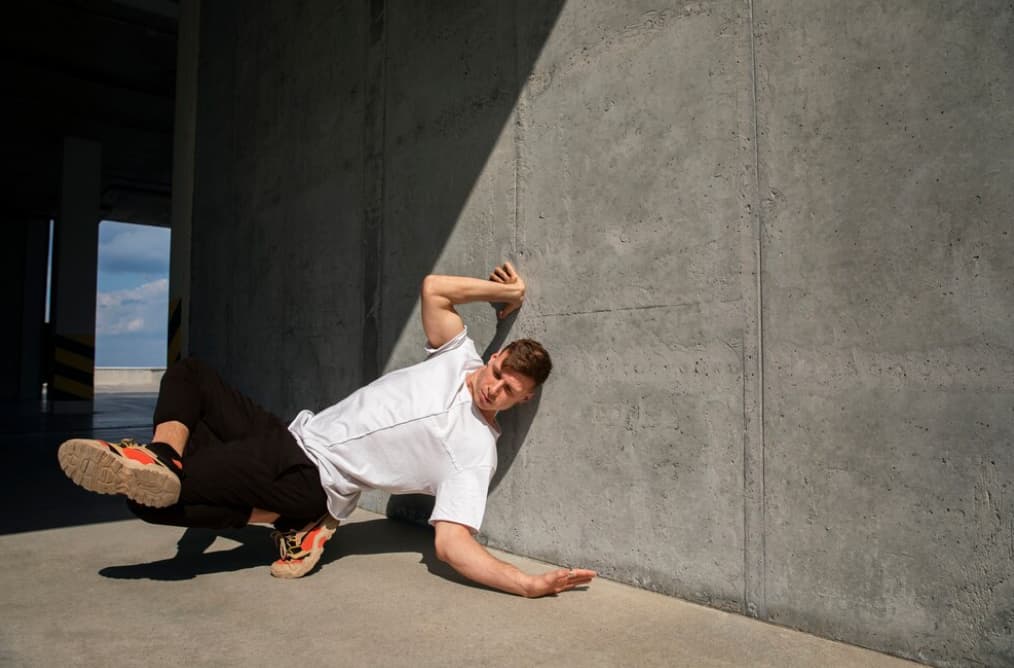 A man falls against a concrete wall in a parking garage