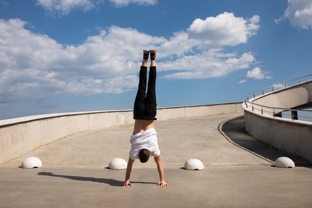 Person performing a handstand on a rooftop walkway