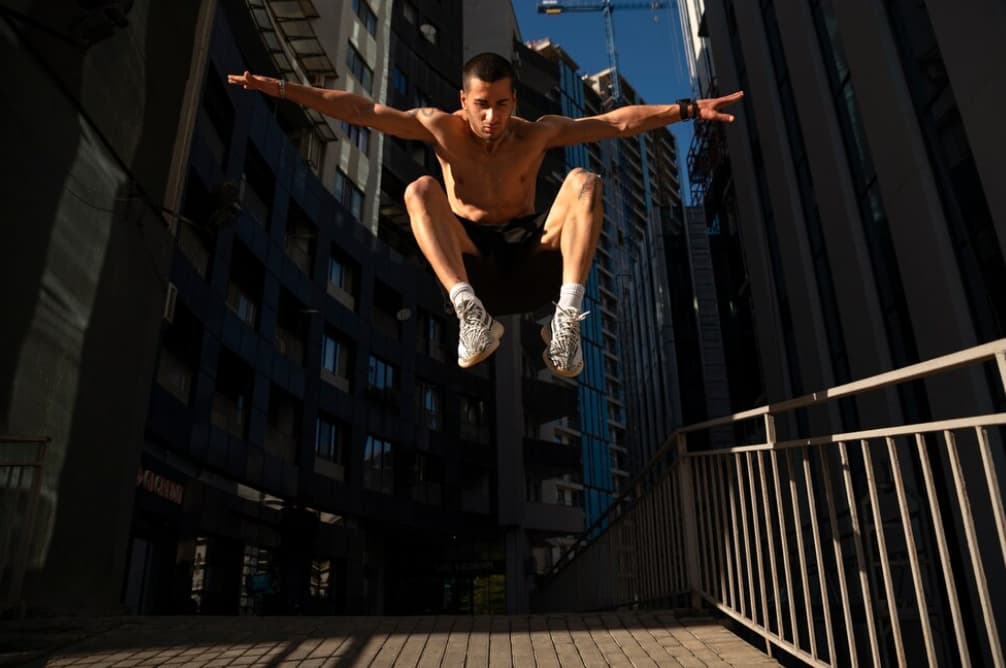 An athlete leaps with buildings in the background